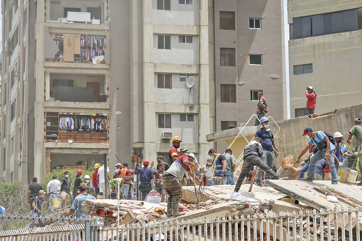 <p>Personas buscan víctimas entre los escombros de un edificio derrumbado en Caracas. Foto: Reuters</p>