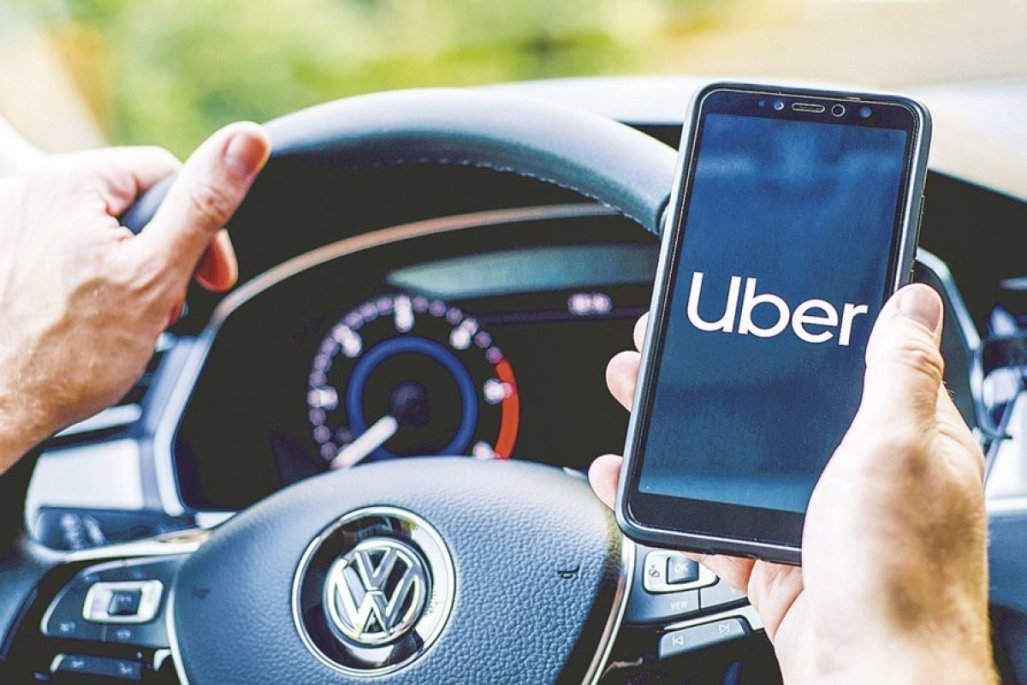 Driver holding a smartphone showing the Uber app